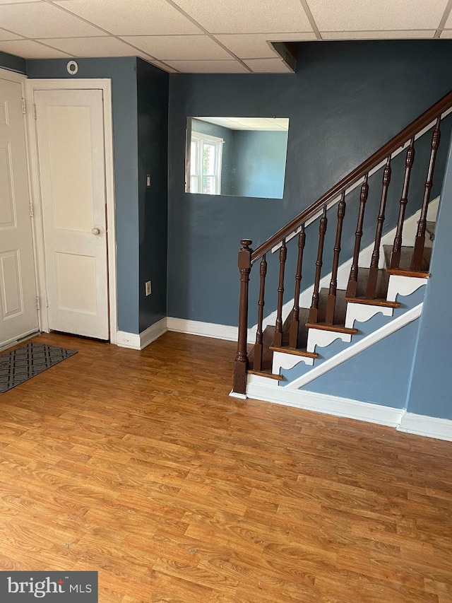 staircase with baseboards, a drop ceiling, and wood finished floors