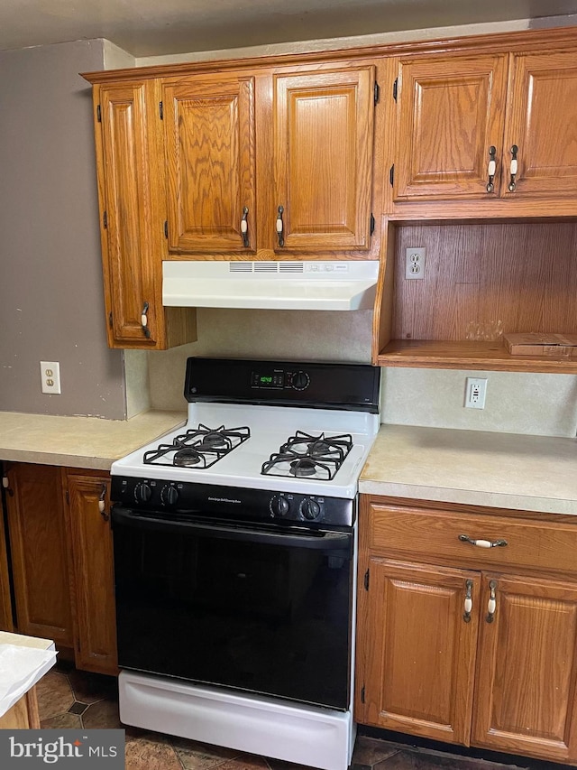 kitchen featuring light countertops, range with gas stovetop, under cabinet range hood, and brown cabinetry