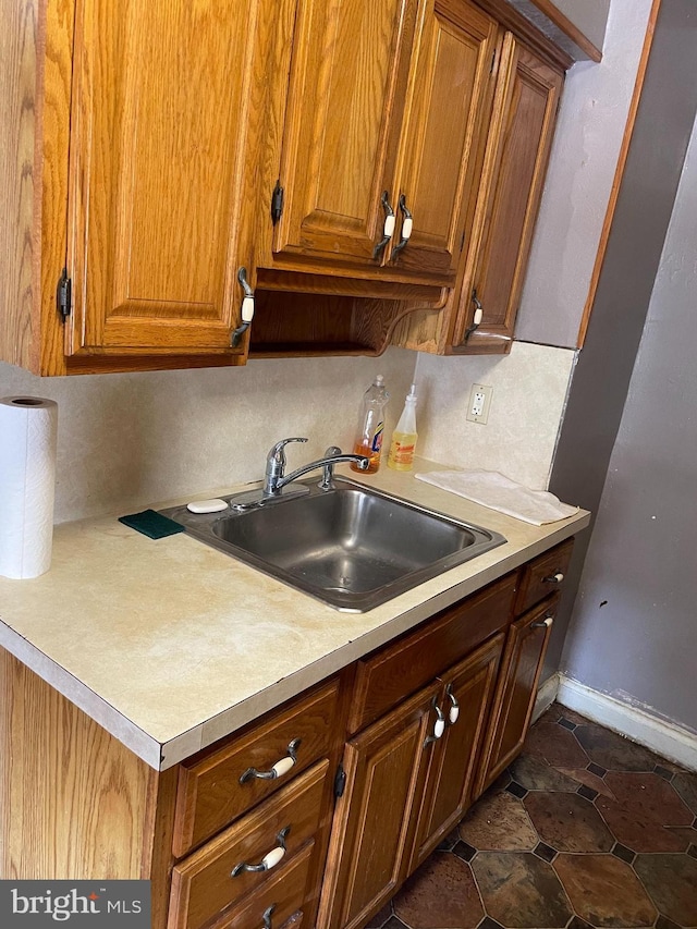 kitchen featuring a sink, brown cabinets, and light countertops