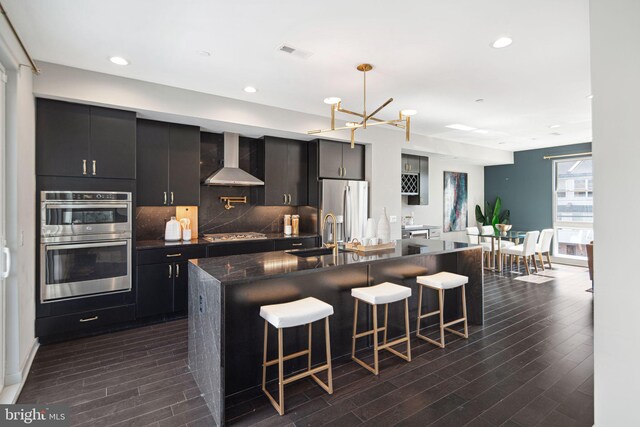 670 N 13th St, Philadelphia, PA 19123 - kitchen featuring a sink, wall chimney range hood, stainless steel appliances, dark wood finished floors, and a kitchen breakfast bar