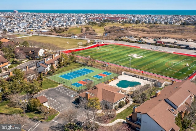 aerial view of residential area featuring a pool and a large body of water