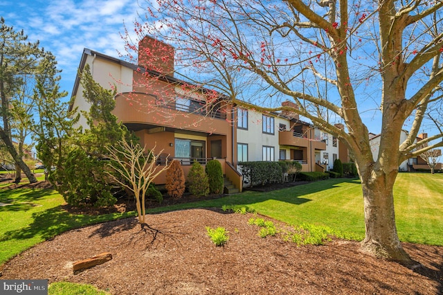 view of front of property featuring a chimney, stucco siding, and a front lawn