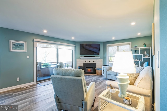 living room featuring healthy amount of natural light, wood finished floors, a fireplace, recessed lighting, and baseboards