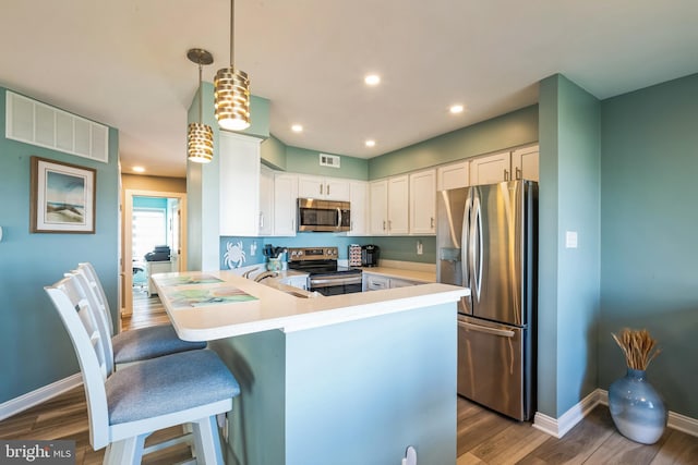kitchen featuring stainless steel appliances, white cabinetry, dark wood-type flooring, baseboards, and a kitchen bar
