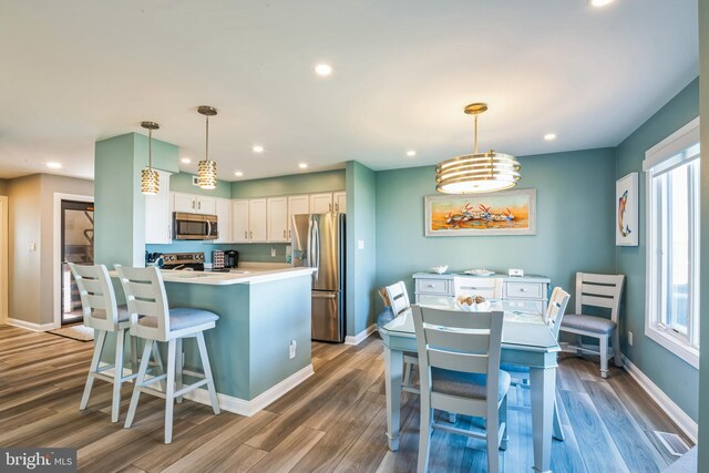 kitchen with stainless steel appliances, white cabinets, baseboards, wood finished floors, and recessed lighting