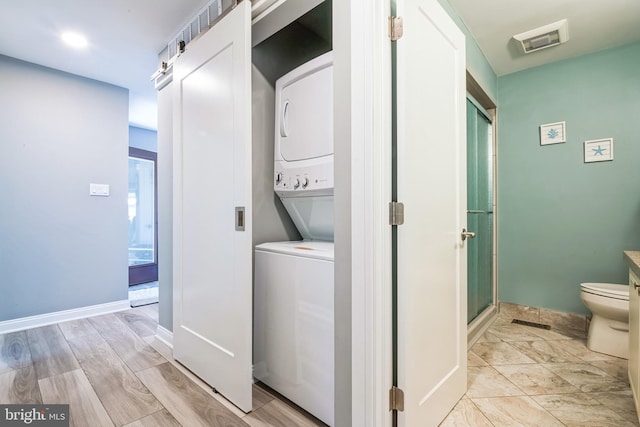 laundry area with stacked washer / drying machine and baseboards