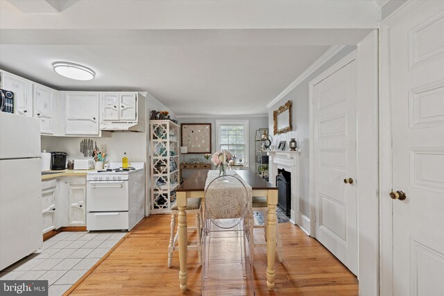 328 S Juniper St, Philadelphia, PA 19107 - kitchen featuring under cabinet range hood, ornamental molding, white appliances, white cabinetry, and a fireplace with flush hearth
