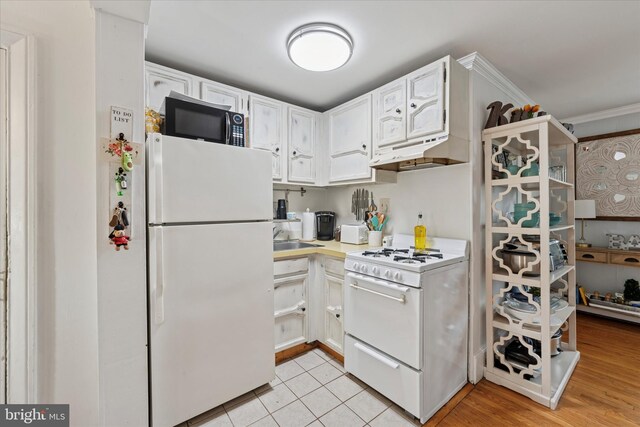 328 S Juniper St, Philadelphia, PA 19107 - kitchen featuring light tile patterned floors, white cabinetry, white appliances, under cabinet range hood, and light countertops