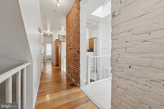 328 S Juniper St, Philadelphia, PA 19107 - hallway featuring brick wall, a skylight, and light wood-type flooring