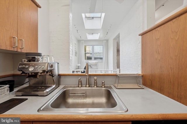 328 S Juniper St, Philadelphia, PA 19107 - kitchen with light countertops, brick wall, a skylight, and a sink