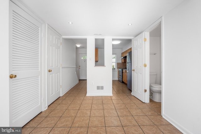 kitchen with appliances with stainless steel finishes, light tile patterned floors, baseboards, recessed lighting, and under cabinet range hood