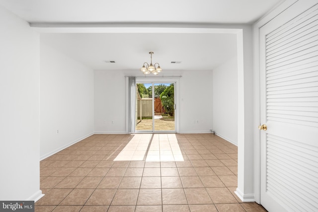 unfurnished room featuring a chandelier, light tile patterned floors, and baseboards