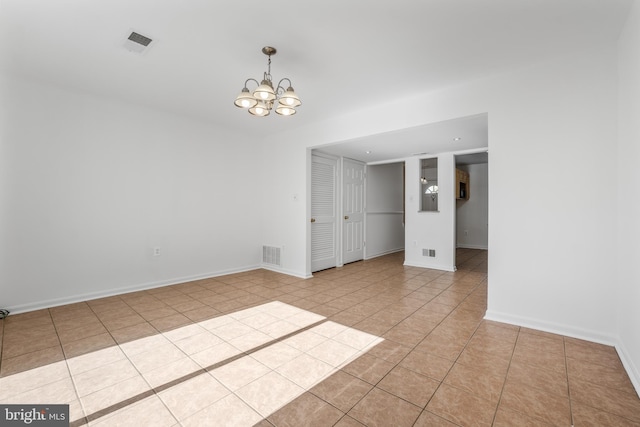 unfurnished room featuring a chandelier, light tile patterned floors, and baseboards