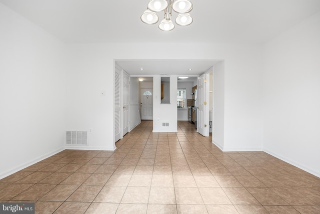 unfurnished room with a chandelier, light tile patterned floors, and baseboards
