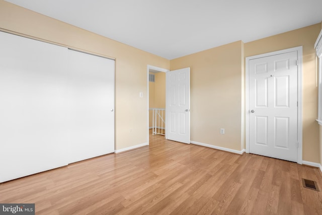 unfurnished bedroom with light wood-type flooring, baseboards, and a closet