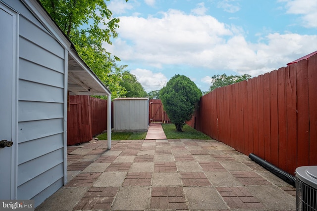 view of patio / terrace with a fenced backyard, a storage unit, an outbuilding, and central AC