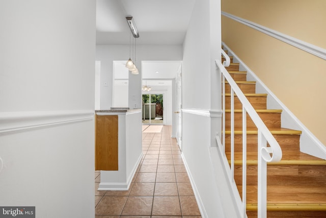 hallway featuring light tile patterned floors, stairs, and baseboards