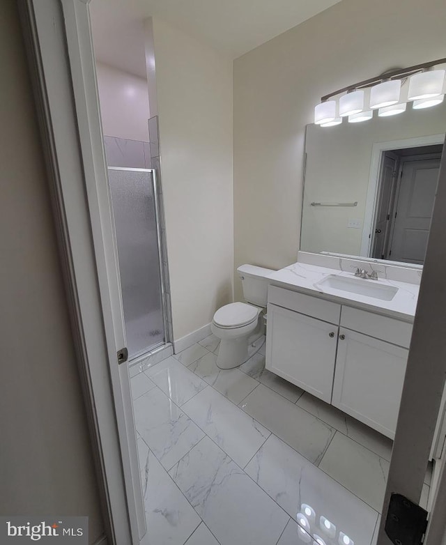 bathroom featuring vanity, toilet, marble finish floor, baseboards, and a stall shower
