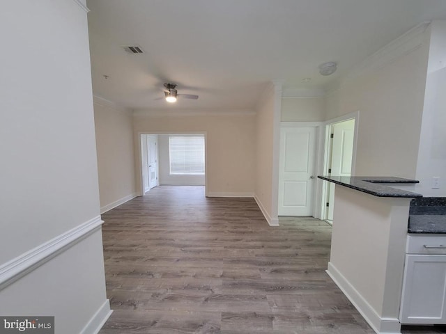 interior space with visible vents, ornamental molding, baseboards, and wood finished floors