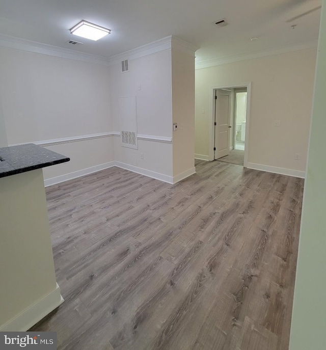 basement with ornamental molding, light wood-type flooring, and visible vents