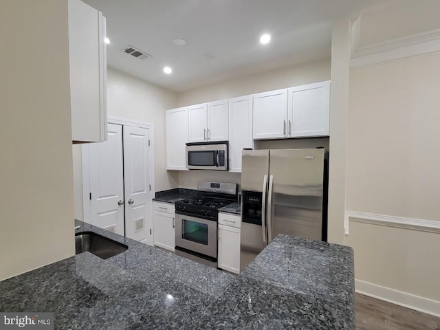 kitchen with a sink, appliances with stainless steel finishes, white cabinetry, and visible vents
