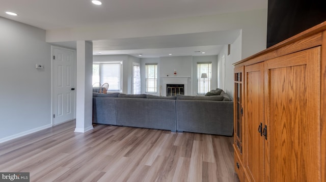 living room featuring light wood-type flooring, baseboards, a glass covered fireplace, and recessed lighting