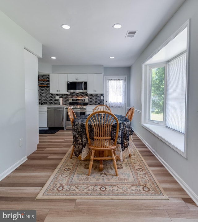 dining space with light wood-style flooring, recessed lighting, and baseboards
