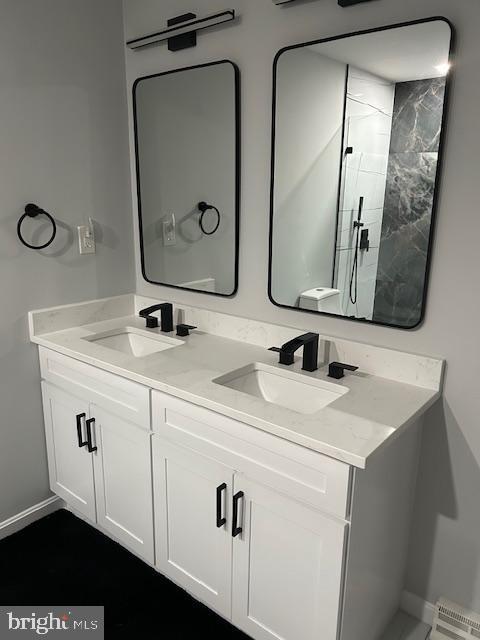 full bathroom featuring double vanity, baseboards, and baseboard heating