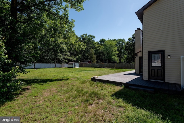 view of yard featuring a storage shed, a deck, and an outbuilding