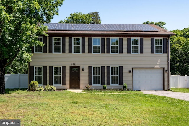 colonial house with driveway, a garage, and solar panels