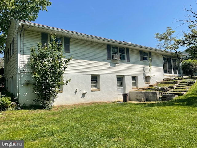 rear view of house with stucco siding, a sunroom, stairway, cooling unit, and a lawn