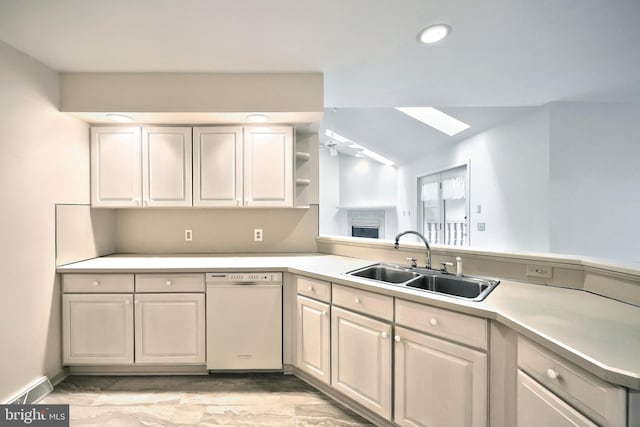 kitchen featuring a skylight, dishwasher, a sink, light countertops, and marble finish floor