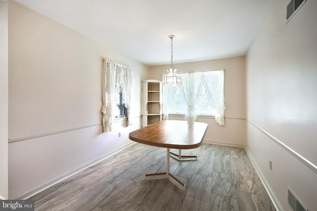 dining area featuring a notable chandelier, visible vents, and baseboards
