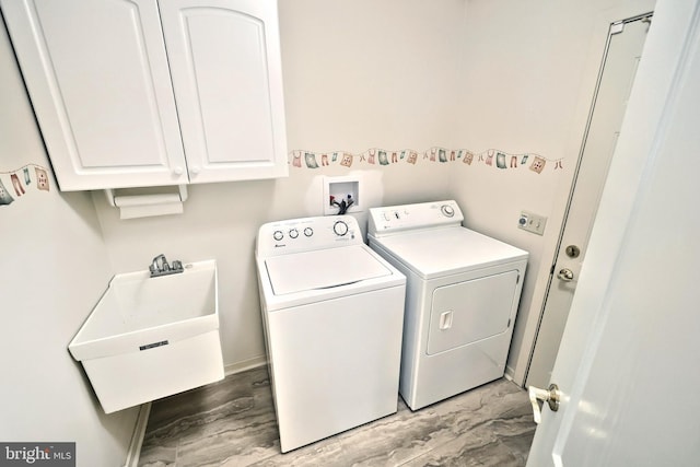 laundry room featuring cabinet space, a sink, baseboards, wood finished floors, and washer and clothes dryer