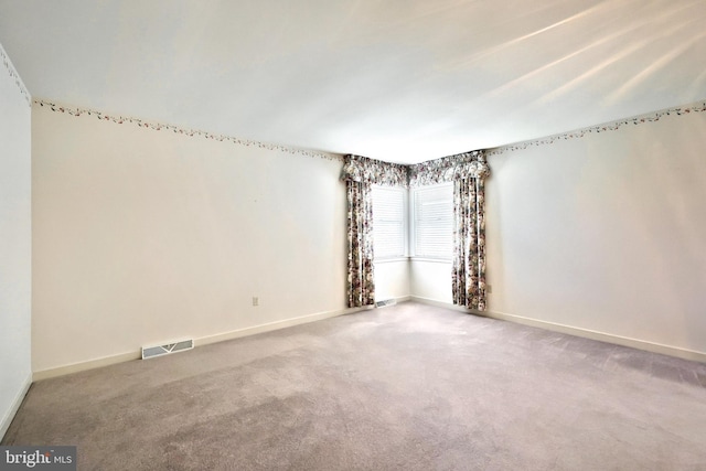 carpeted empty room featuring baseboards and visible vents
