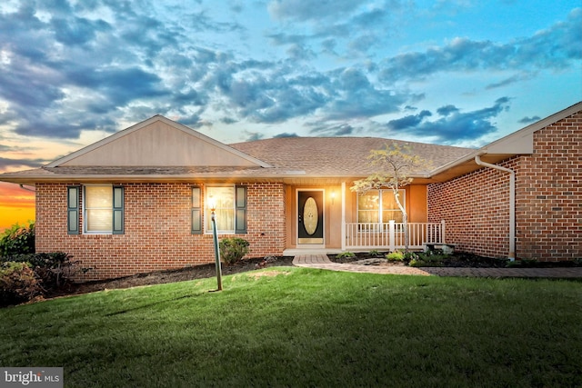 single story home with covered porch, a front yard, and brick siding
