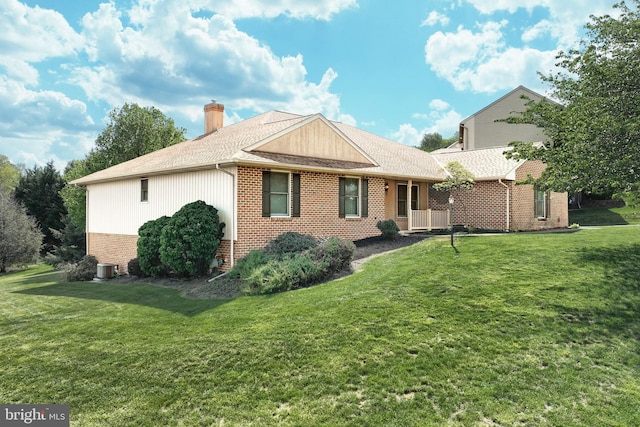 back of property featuring brick siding, a lawn, roof with shingles, and a chimney