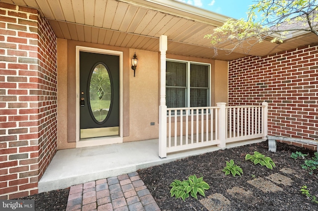 property entrance featuring covered porch and brick siding