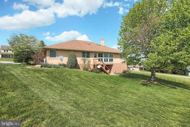 rear view of house with a yard, a chimney, stairs, and stucco siding