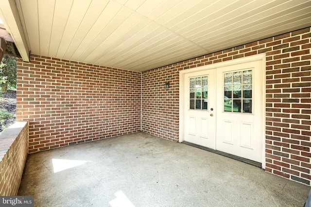 view of exterior entry with brick siding and a patio area
