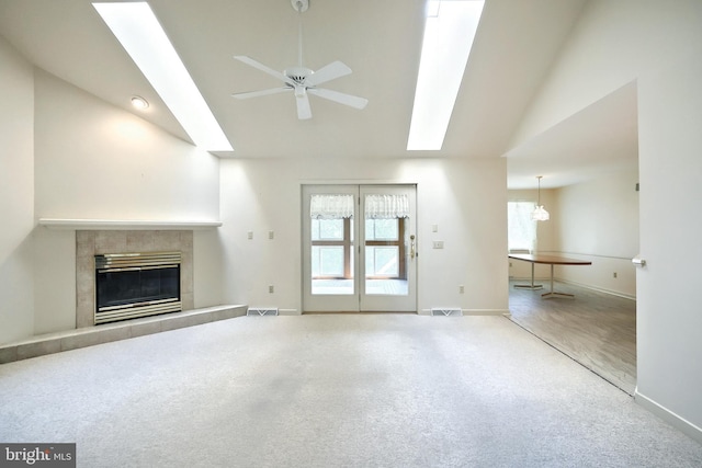unfurnished living room featuring visible vents, vaulted ceiling with skylight, and a healthy amount of sunlight