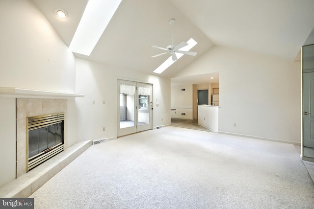 unfurnished living room featuring ceiling fan, visible vents, a skylight, high vaulted ceiling, and light carpet