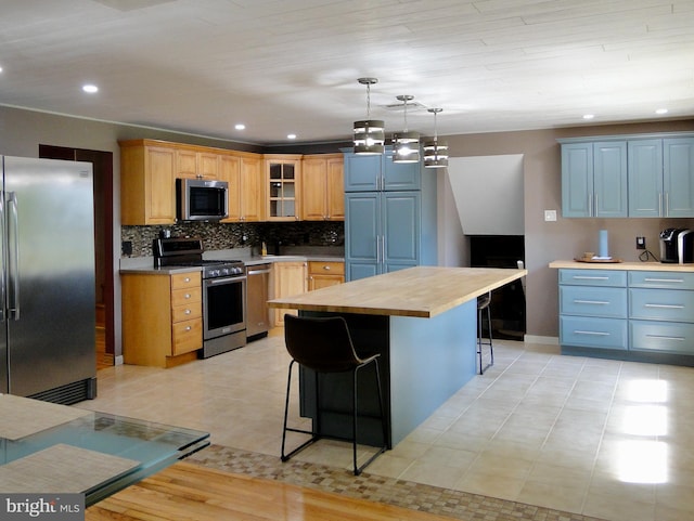 kitchen featuring stainless steel appliances, tasteful backsplash, a breakfast bar, glass insert cabinets, and hanging light fixtures