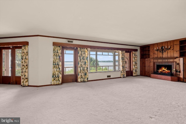 unfurnished living room featuring baseboards, healthy amount of natural light, ornamental molding, a brick fireplace, and carpet