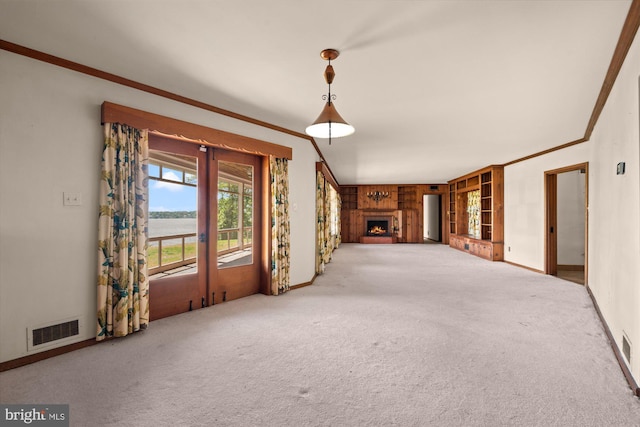 unfurnished living room with carpet, ornamental molding, baseboards, french doors, and a warm lit fireplace