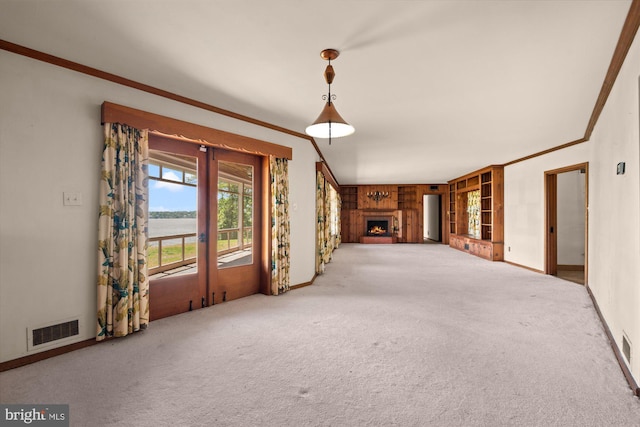 unfurnished living room featuring ornamental molding, carpet flooring, baseboards, a lit fireplace, and french doors