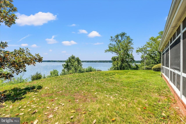 view of green lawn with a water view and a sunroom