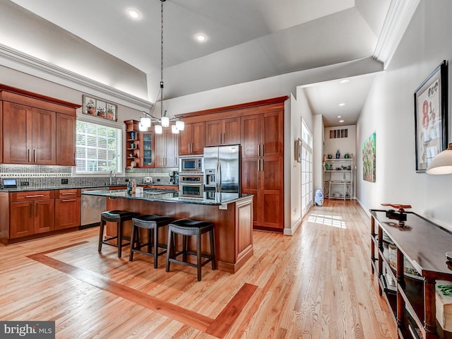 26 Bellchase Ct Unit B, Pikesville, MD 21208 - kitchen with appliances with stainless steel finishes, a center island, a kitchen bar, backsplash, and light wood-type flooring