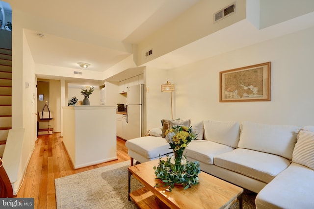 living area featuring stairway and light wood-style flooring