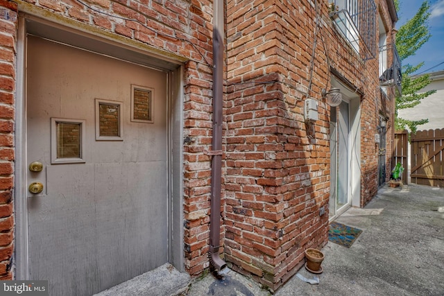property entrance with brick siding and fence